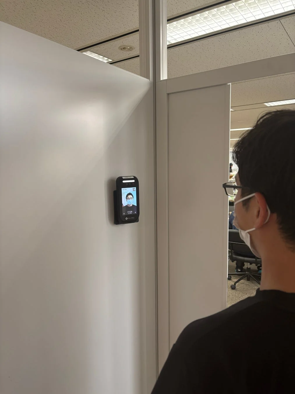 顔認証・体温測定デバイスを利用するマスク姿の人物